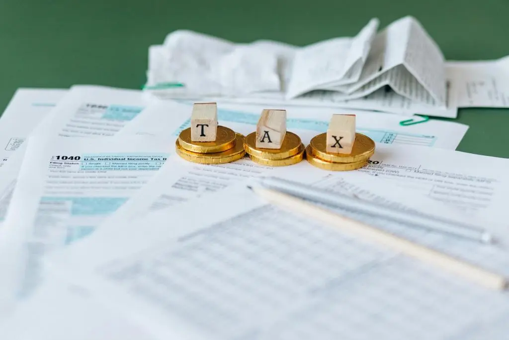 Scattered forms on a table and letter cubes spelling out the word Tax